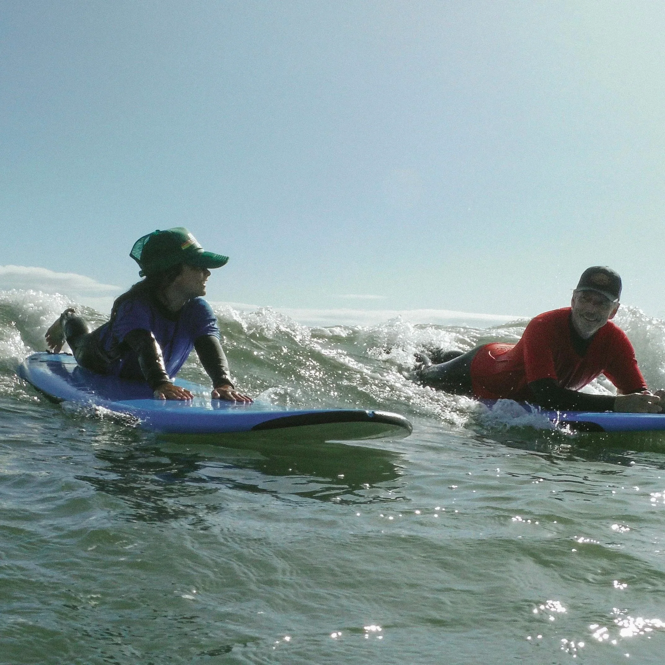 MTC Surf participant and instructor riding through the surf together